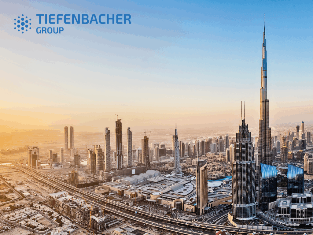 Tiefenbacher Group - A panoramic cityscape of Dubai with the Burj Khalifa towering over other skyscrapers at sunset, highlighting the Tiefenbacher Group—a family-owned pharmaceutical company known for API distribution—in the upper left corner.