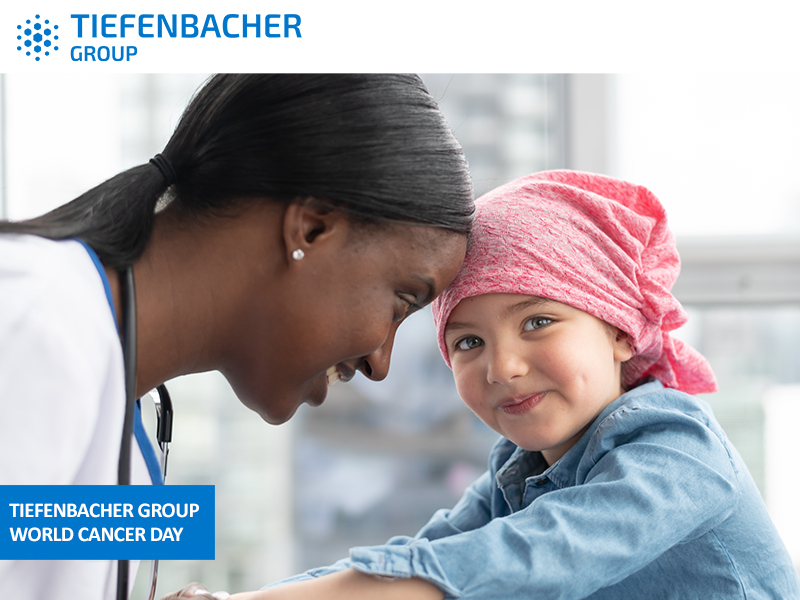 Tiefenbacher Group - A doctor smiles warmly at a young child wearing a pink headscarf in a bright medical setting, reflecting TIEFENBACHER GROUP’s commitment to pharmaceutical healthcare solutions on World Cancer Day.